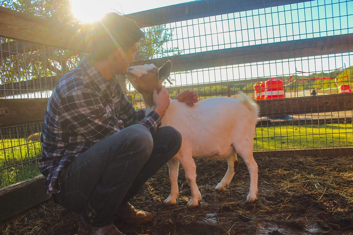 Man kissing goat at Bob's House of Hope